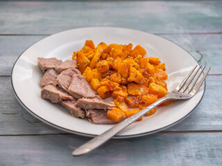 Light breakfast with fried pumpkin and boiled turkey slices with a fork