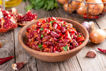 Georgian cuisine. Mingrelian lobio. Appetizer of stewed red beans, onions, garlic, spices and herbs in a plate on a wooden background. Background image, copy space. Restaurant menu. Horizontal