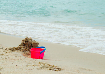 A bucket of red sand on the beach and the blue sea landscape.