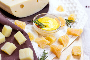 Fresh homemade creamy cheese sauce in a glass bowl with rosemary and parmesan pieces on light...