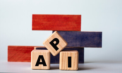 API - acronym on wooden cubes on a background of colored block on a light background