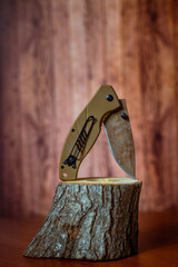 folding hunting knife on wood on brown background