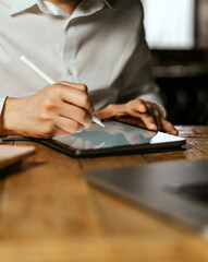 Male hands drawing on digital tablet with electronic pen. Freelancer designer working remotely. Close-up photo
