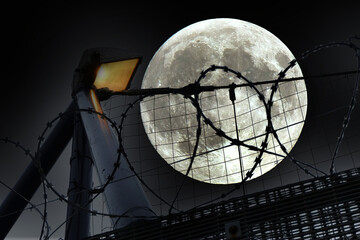 security light and fencing to protect building from unauthorised access. moon added for dramatic effect.