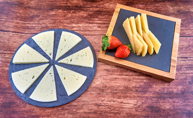 TABLA DE QUESOS IB&Eacute;RICOS CON FRESAS SOBRE FONDO  DE MADERA
