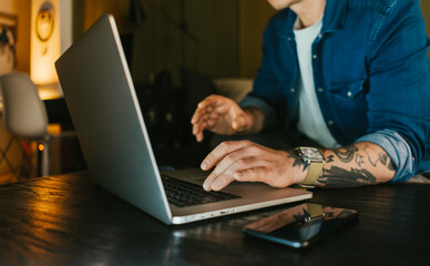 Close-up of male hands with laptop. Man is working remotely at home. Freelancer at work