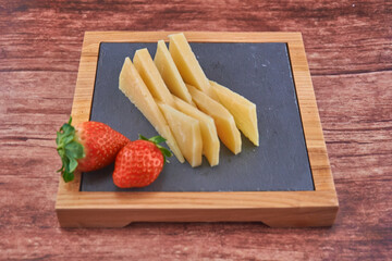 TABLA DE QUESOS IB&Eacute;RICOS CON FRESAS SOBRE FONDO  DE MADERA
