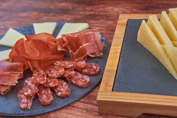 TALA DE QUESOS, JAM&Oacute;N IB&Eacute;RICO, LOMO Y FUET SOBRE FONDO DE MADERA