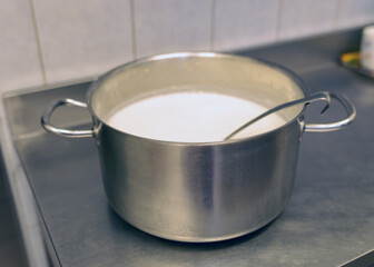 metal pot with cup on stove top with milk soup, school kitchen, eat cooking concept