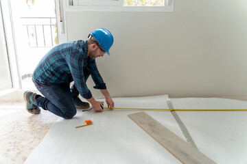 Carpenter worker installing laminate flooring in the room.
