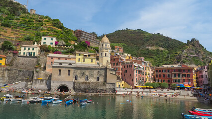 Fototapeta na wymiar Italian National park, Parco Nazionale delle Cinque Terre, province of La Spezia, Liguria region, Italy. Amazing seashore of Vernazza with colorful houses, small boats and vineyards on mountain slopes