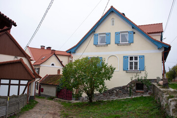 Old German houses with wooden windows and wrought-iron lanterns on the central street of the village of Zheleznodorozhny.