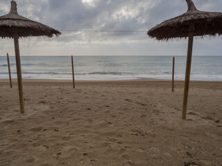 Mediterranean Sea views from the beach next to a straw umbrella in winter