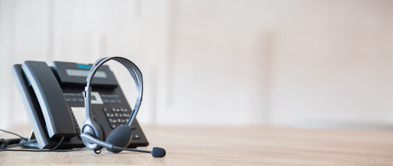 Communication support, call center and customer service help desk. VOIP headset on telephone keyboard.