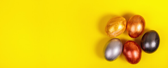 Multi-colored eggs on a uniform yellow background with place for text.