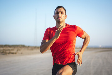 Young fit male athlete sprinting and training outdoors at sunset