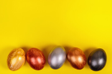 Multi-colored eggs on a uniform yellow background with place for text.