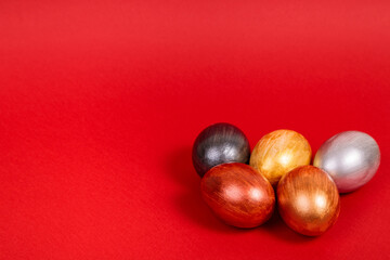 Multi-colored eggs on a uniform red background with place for text.