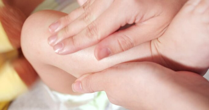 Mom is rubbing the baby acne ointment on the little boy's leg