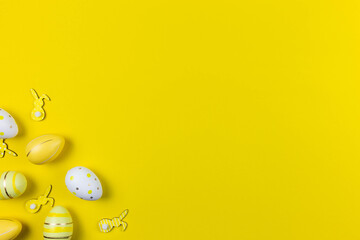 Colorful easter painted eggs and bunnies background on yellow colorful background flat lay. Easter holiday concept. Traditional decoration for springtime holiday. Top view. Copy space.