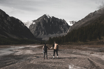two hikers hold hands in front of the snowy mountain