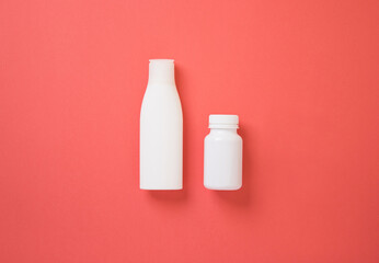 White pill and face cream bottle mockup on pink background, plastic bottle to place label