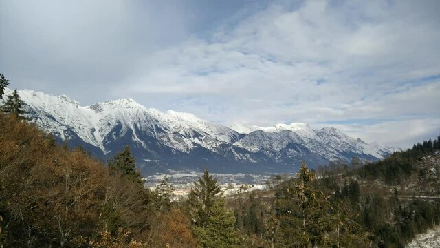 A time-lapse of the Nordkette Range surrounded by trees under a cloudy sky in Innsbruck, Austria shot in 4K