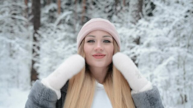 Portrait of a beautiful girl in a pink hat in winter in a snowy forest, smile and happiness concept
