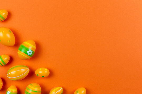 Colorful easter painted eggs background on orange colorful background flat lay. Easter holiday concept. Traditional decoration for springtime holiday. Top view. Copy space.