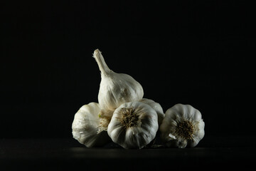 heap garlic bulbs on black background