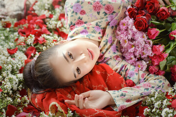 Valentine's Day. Loving girl. The girl in a red dress lying on the floor in the petals of red roses.Beautiful woman with red rose petals,