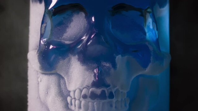 Blue Glass Skull in Frost. A glass vessel with a bright, rich amethyst-blue content in the form of a glass skull, cooled by liquid evaporating nitrogen
