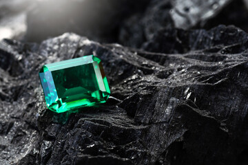 raw emeralds, gemstone jewelry on black coal background