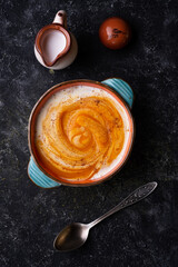 baked pumpkin cream coup with  coconut milk served in nice bowl at wooden black table. flat lay. cooking and healthy life concept