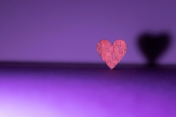 purple background with isolated heart in focus and with its shadow