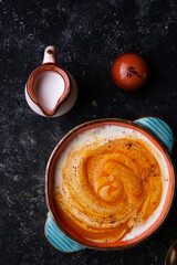 baked pumpkin cream coup with  coconut milk served in nice bowl at wooden black table. flat lay. cooking and healthy life concept