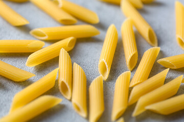Uncooked yellow pasta on gray table. Selective focus. Italian food concept.