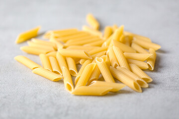 Uncooked yellow pasta on gray table. Selective focus. Italian food concept. Copy space