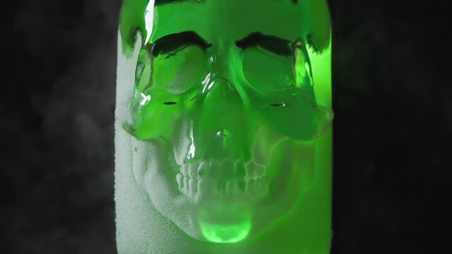Bottle of Poison in Hoarfrost. A glass vessel with a bright, rich emerald-green content in the form of a glass skull, cooled by liquid evaporating nitrogen
