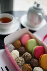 set of truffles and cookies in a box on a table against the background of a teapot