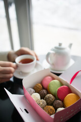 set of truffles and cookies in a box on a table against the background of a teapot