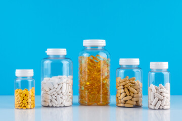 Bottles transparent pills orange capsules blue background. Gel capsules bottle white surface. Nutritional Supplements, Vitamins. Omega 3, multivitamins, Calcium, antibiotics. Health. Immunity