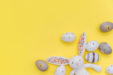 Easter eggs and easter bunny on yellow background. Creative border with copy space.