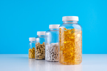 Bottles transparent pills orange capsules blue background. Gel capsules bottle white surface. Nutritional Supplements, Vitamins. Omega 3, multivitamins, Calcium, antibiotics. Health. Immunity