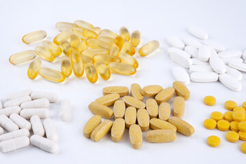 Yellow tablets white capsules gel shell lying on white background close-up. Omega 3, Multivitamins, Calcium, Antibiotics. Health. Immunity. Taking medication, pills. Nutritional supplement. Copy space
