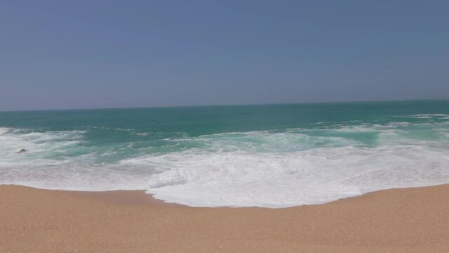 Paisaje de la playa de Nazar&eacute; con las olas rompiendo en la arena