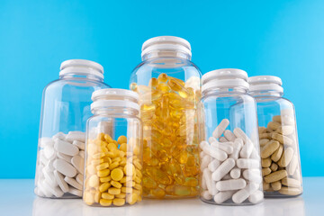 Bottles transparent pills orange capsules blue background. Gel capsules bottle white surface. Nutritional Supplements, Vitamins. Omega 3, multivitamins, Calcium, antibiotics. Health. Immunity