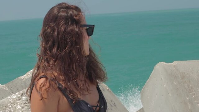 Mujer joven posando en ba&ntilde;ador y vaqueros en Playa de Nazar&eacute;, en Portugal