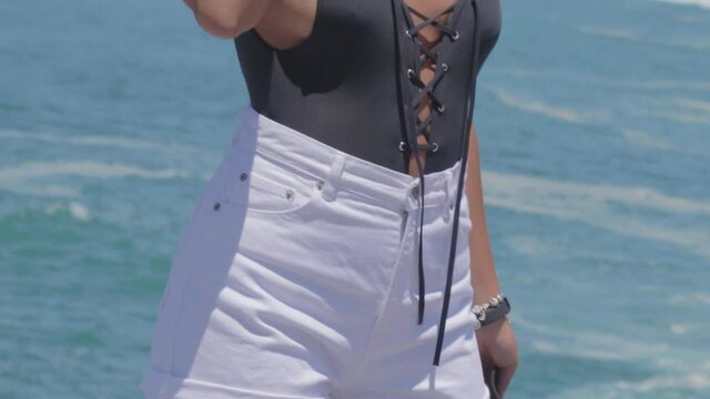 Mujer joven posando en ba&ntilde;ador y vaqueros en Playa de Nazar&eacute;, en Portugal
