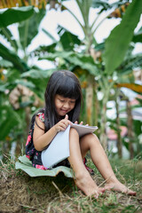 Girl reading a book and studying outdoors at public park in summer